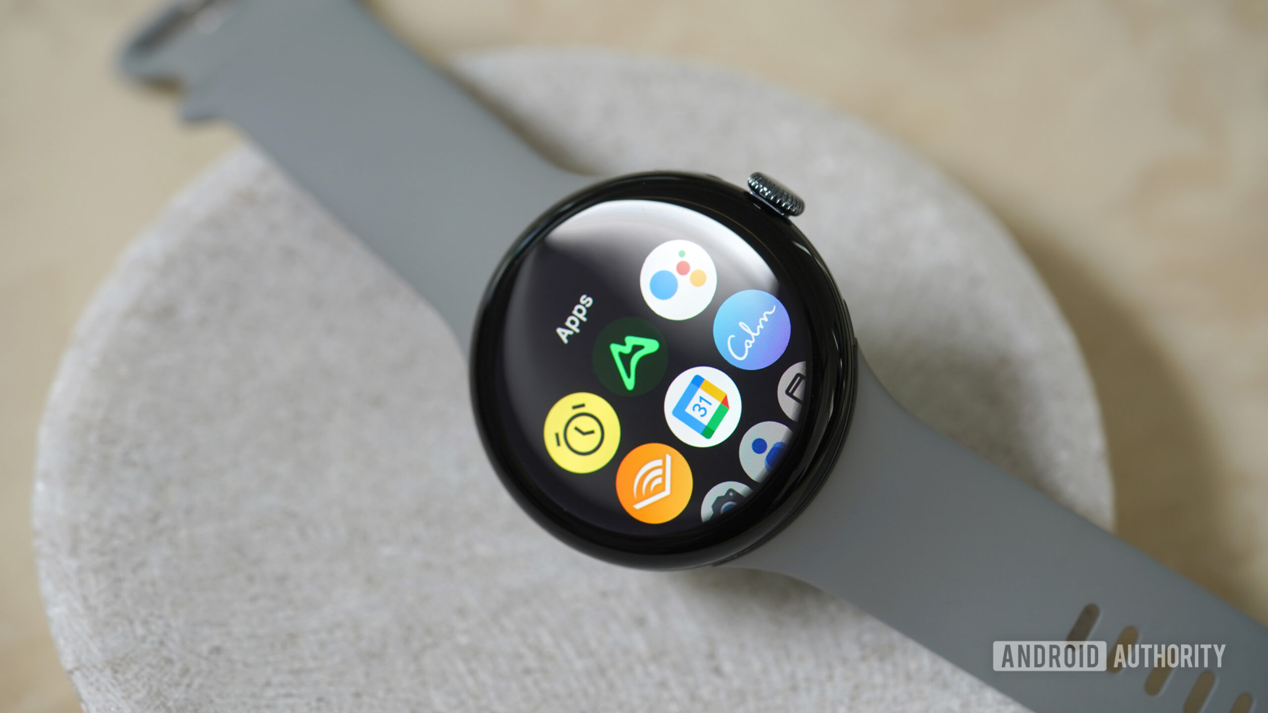 Google Pixel Watch 3 Apps Um relógio do Google Pixel 3 repousa em um prato de pedra, exibindo sua biblioteca de aplicativos.