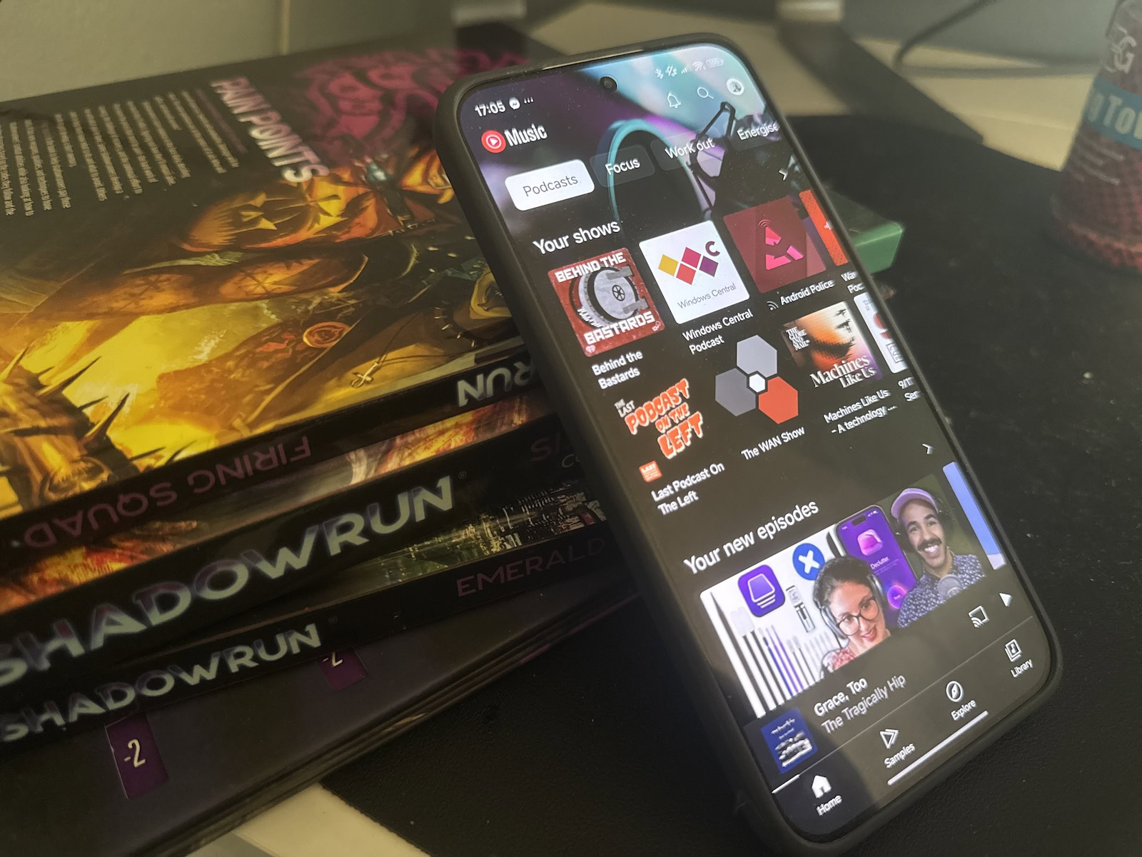 Podcasts de música do YouTube em um dispositivo Android encostado a uma pilha de livros. 