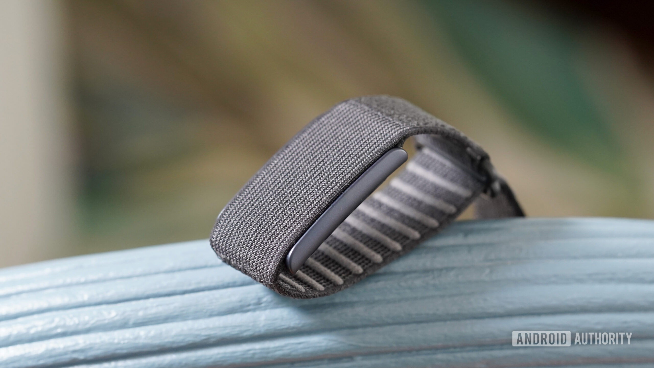 Uma cinta do Amazfit Helio repousa em uma cadeira azul de volta.