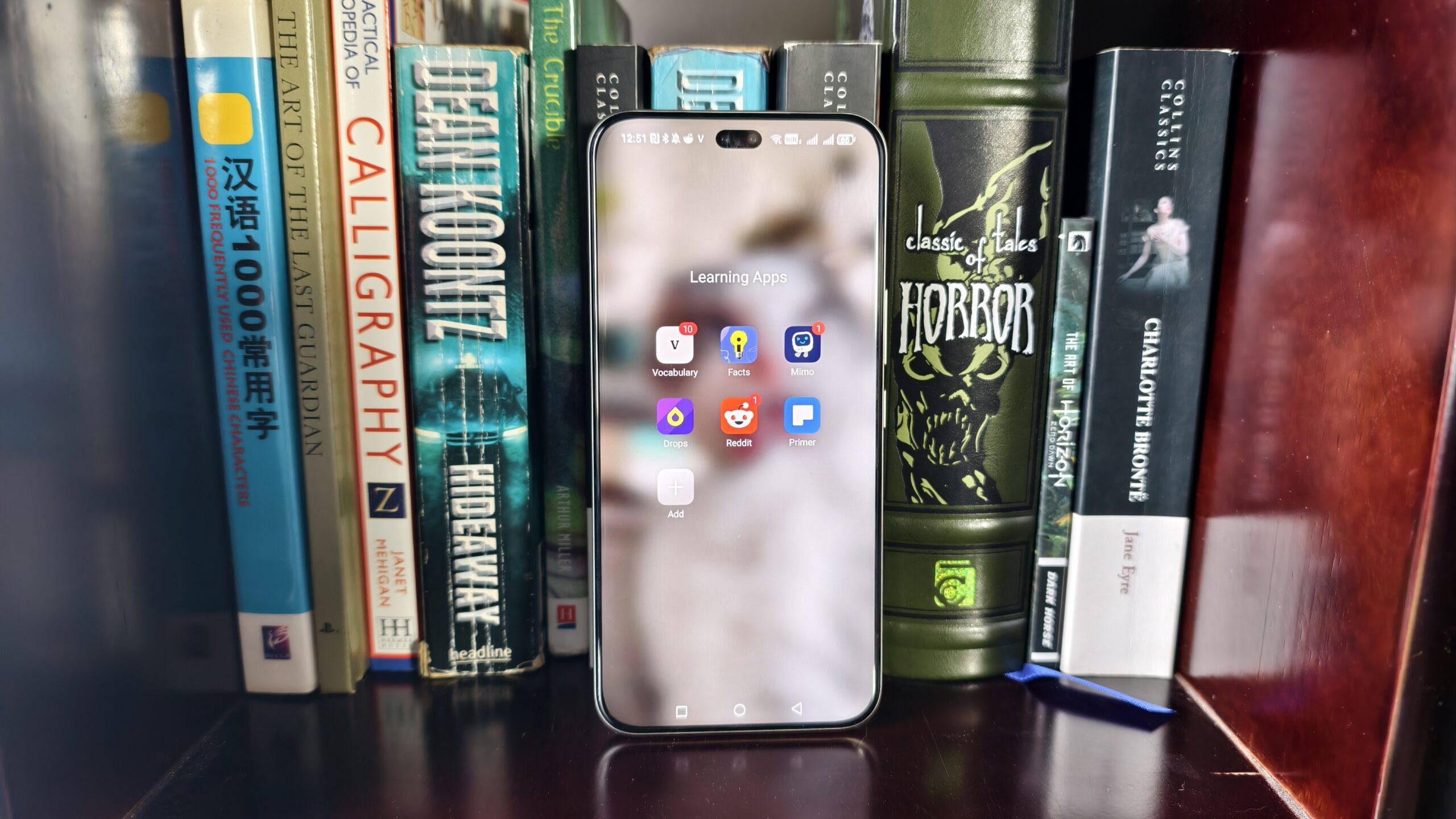 Uma pasta de aplicativos de aprendizado em um smartphone na frente de uma variedade de livros