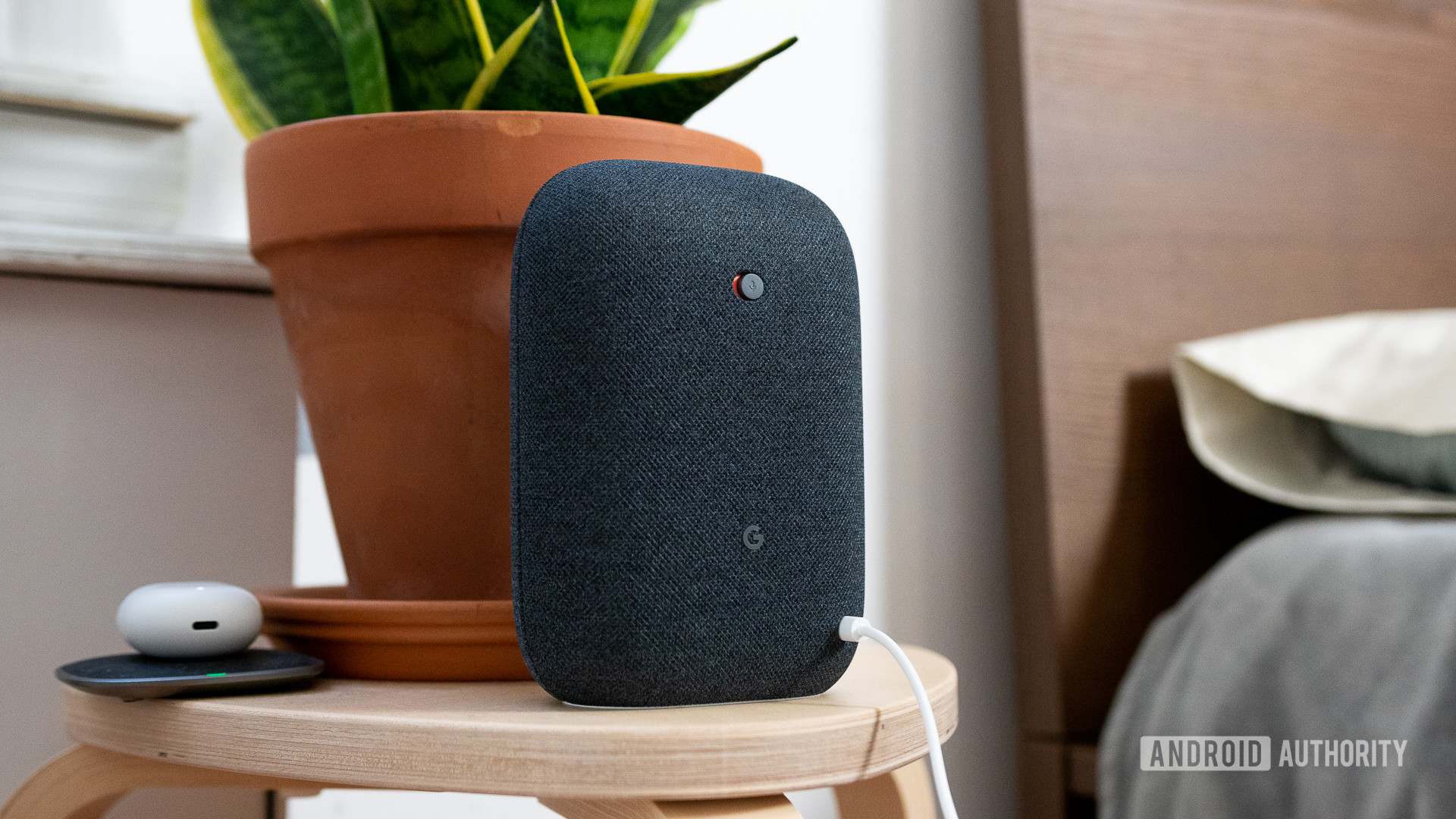 Switch mudo do Google Nest Audio Google Nest Audio em preto na mesa de cabeceira ao lado da cama