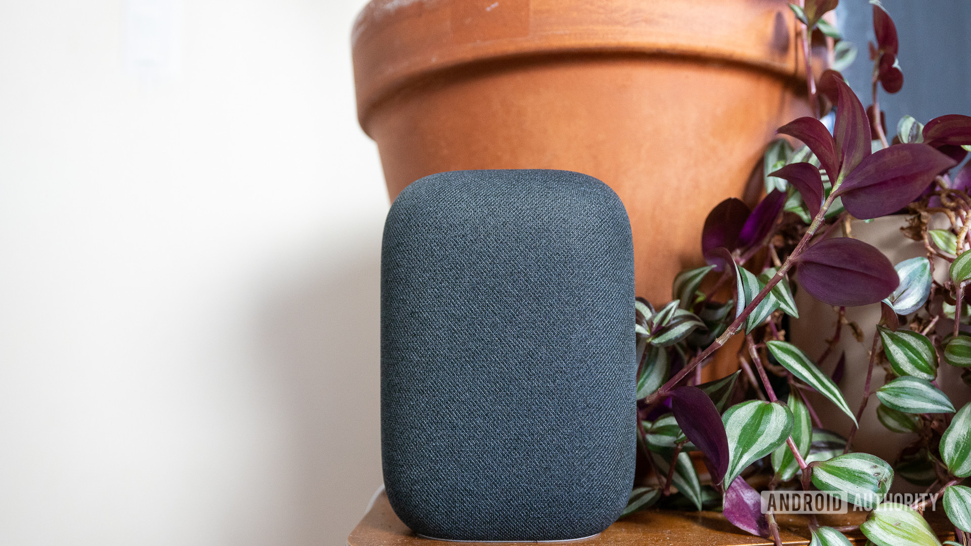 Google Nest Audio Sound O alto -falante do Google Nest Audio em Gray retratado em frente de plantas em uma mesa