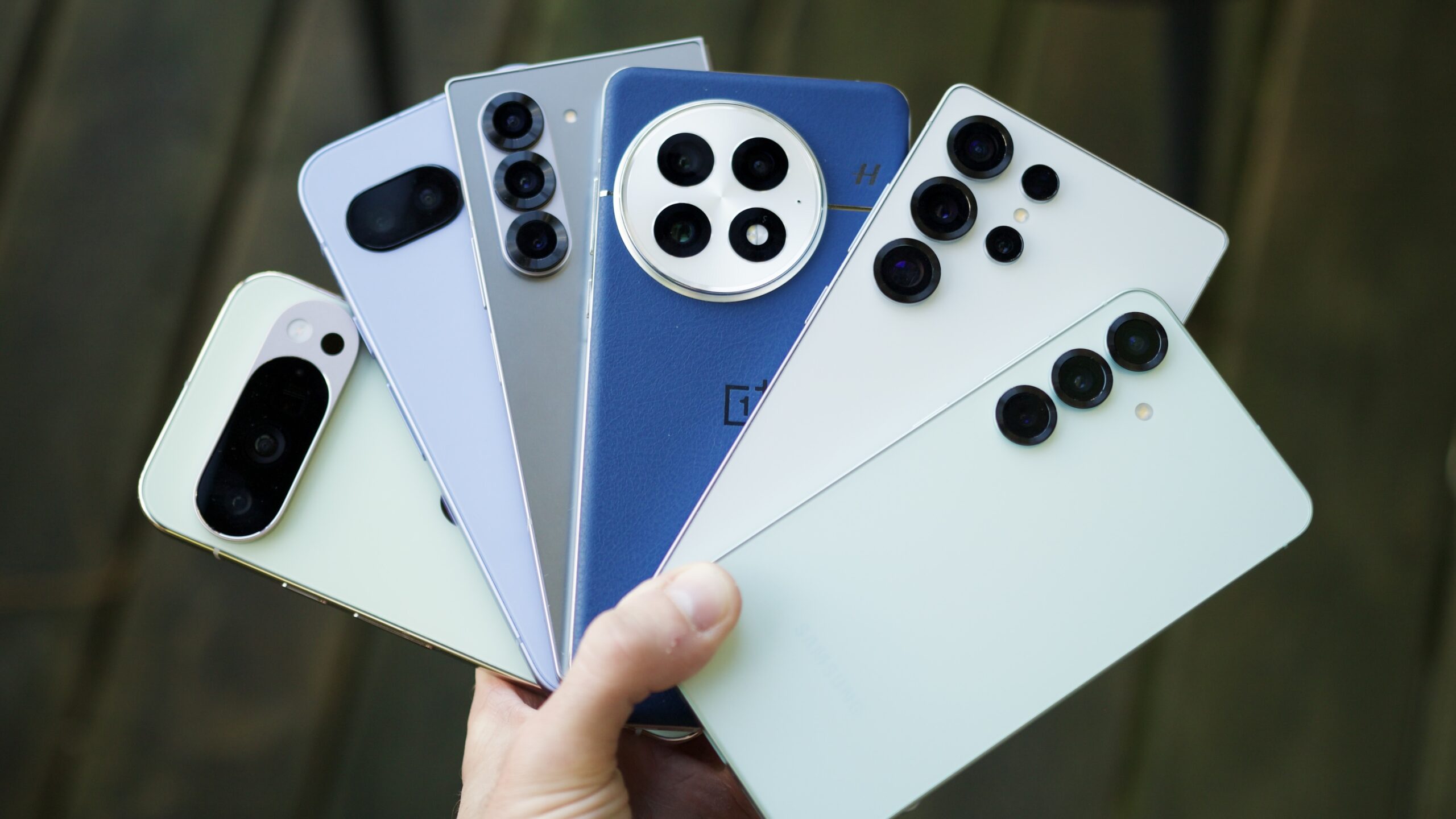 Alguém segurando muitos telefones Android, incluindo aqueles do Google, Samsung e OnePlus.