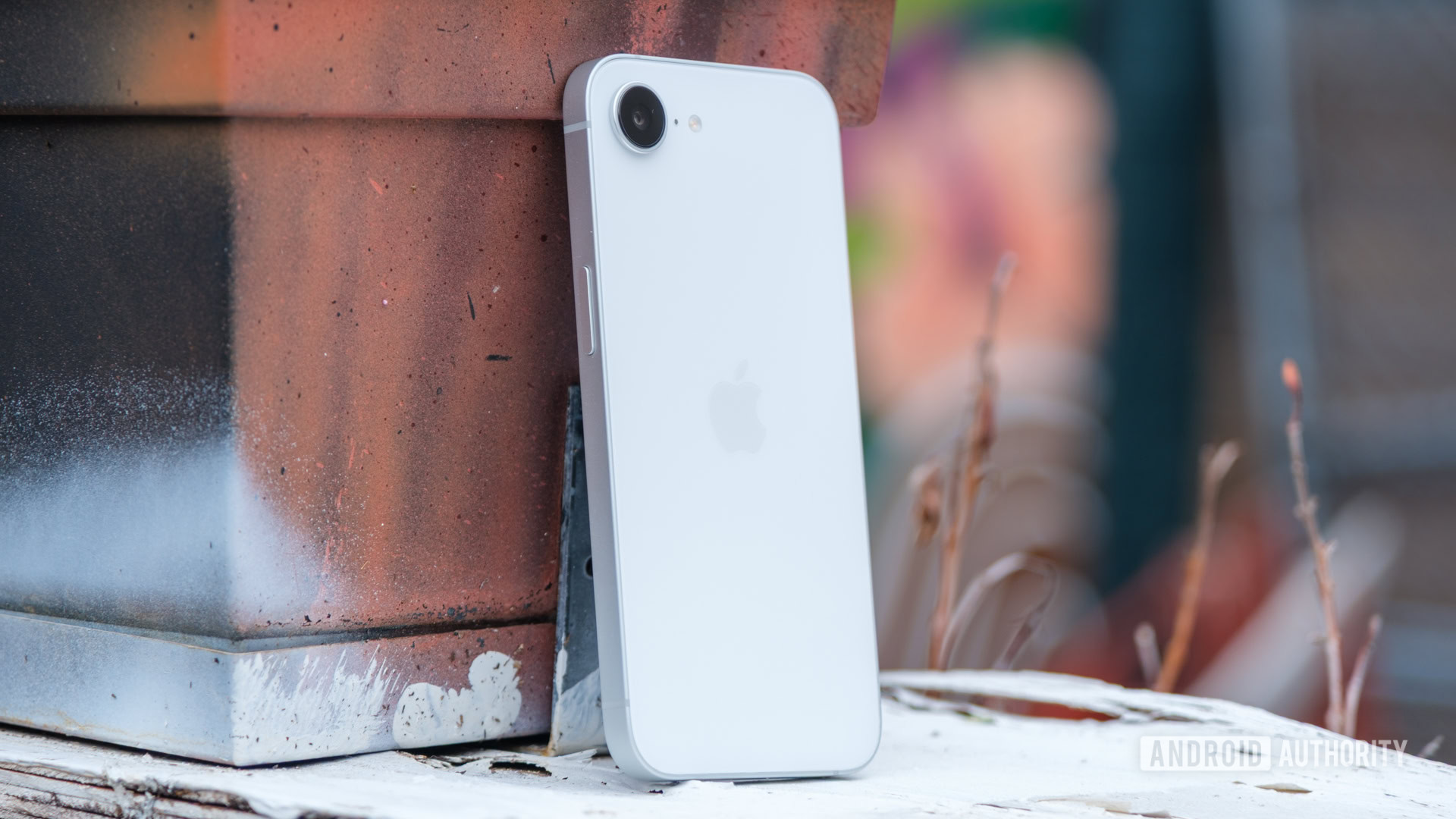 iPhone 16e apoiado em uma floreira