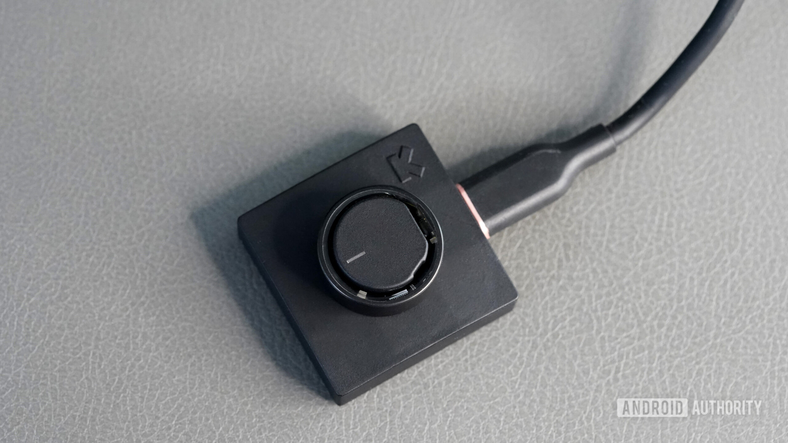 Carregador de ar de anel ultra-humano Um Ultrahuman Ring Air repousa sobre seu carregador tipo disco.