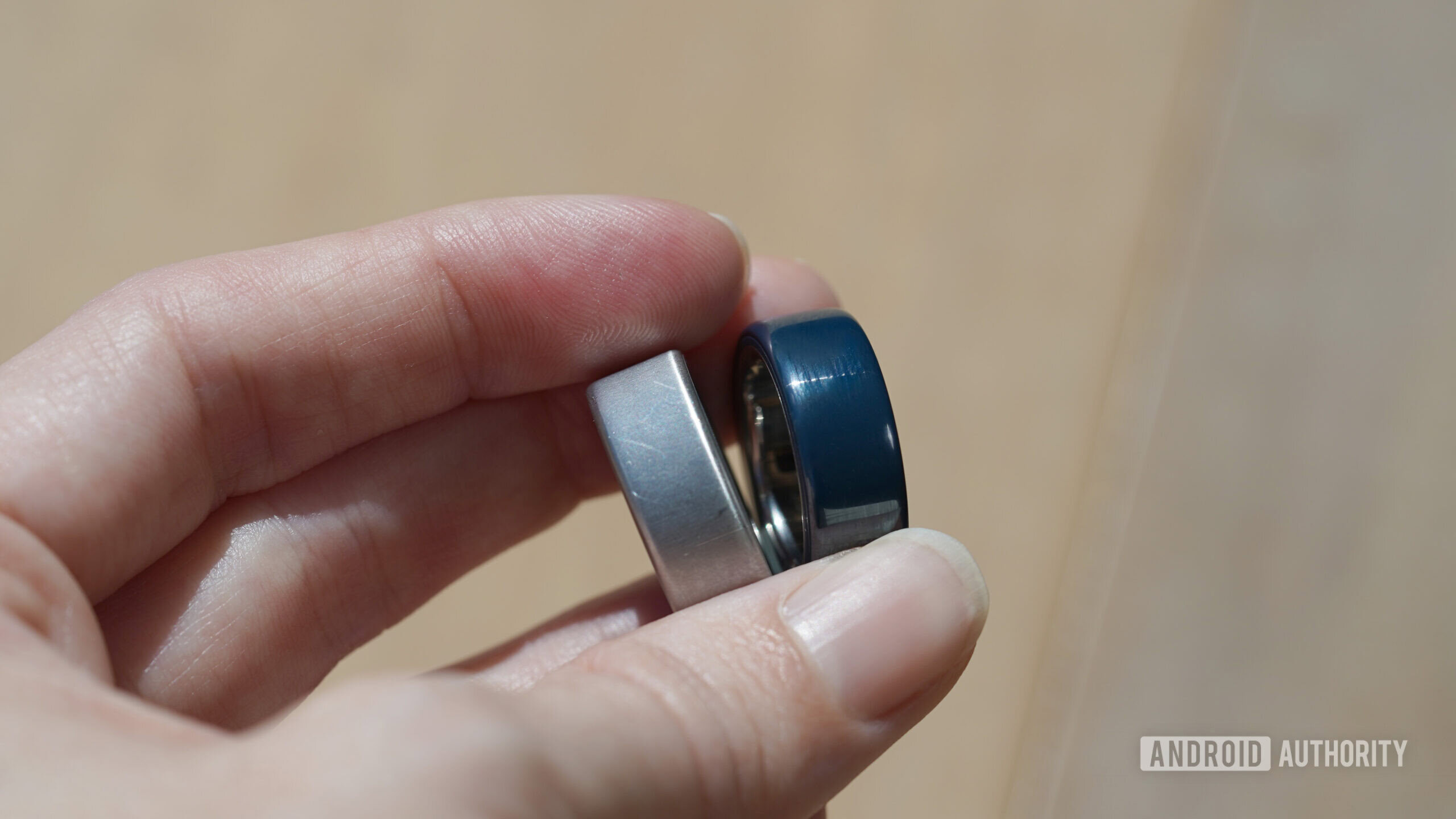 oura anel 4 metal vs cerâmica Um usuário Oura segura um modelo cerâmico e metálico.