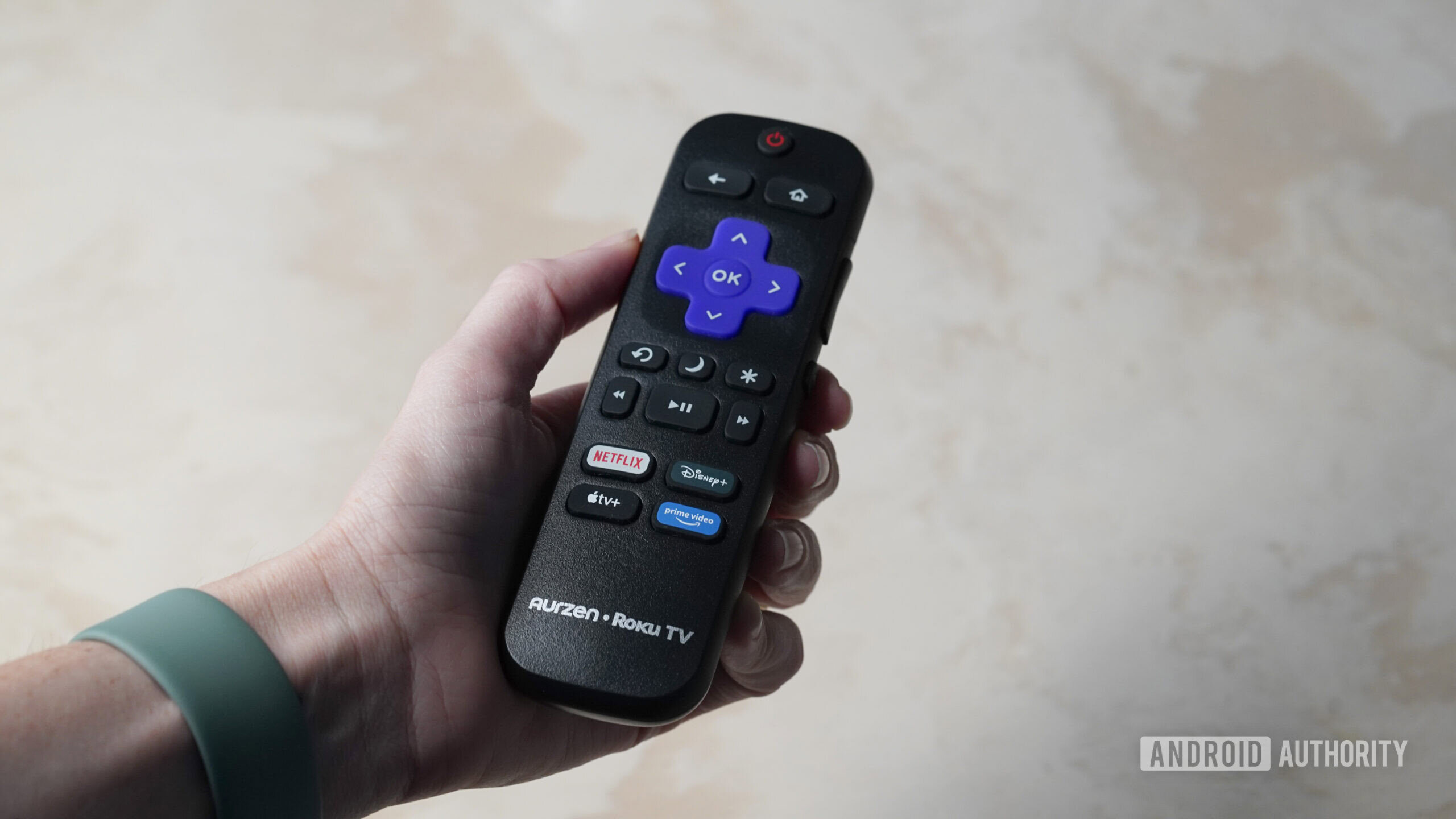Controle remoto Aurzen Roku TV EAZZE D1R Um usuário segura o controle remoto que acompanha o Aurzen Roku TV EAZZE D1R.