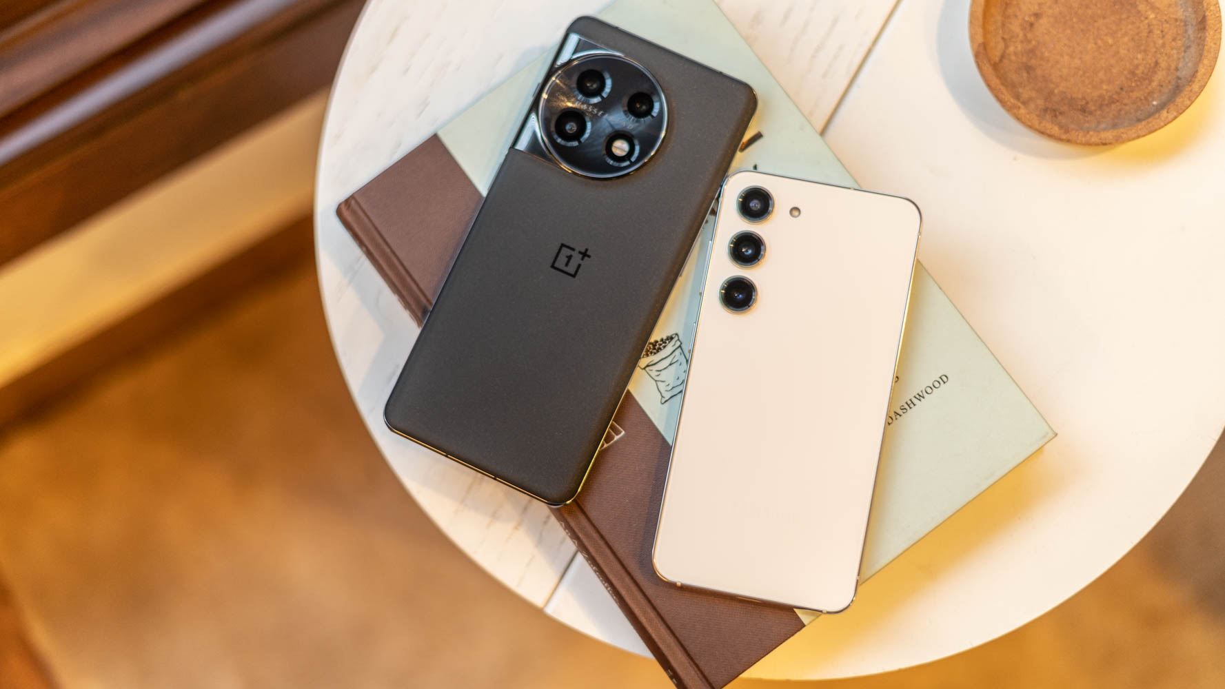 Painéis traseiros OnePlus 11 vs Samsung Galaxy S23 colocados em um livro