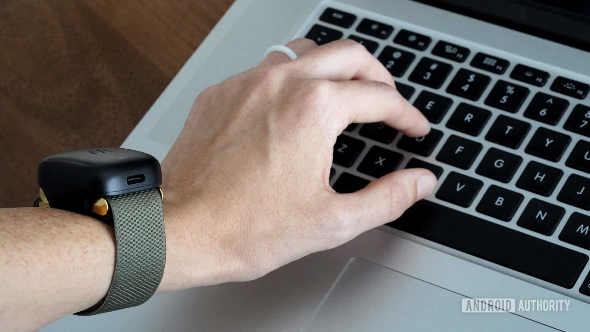 Um usuário do WHOOP 4.0 digita em seu laptop com a bateria do dispositivo conectada.