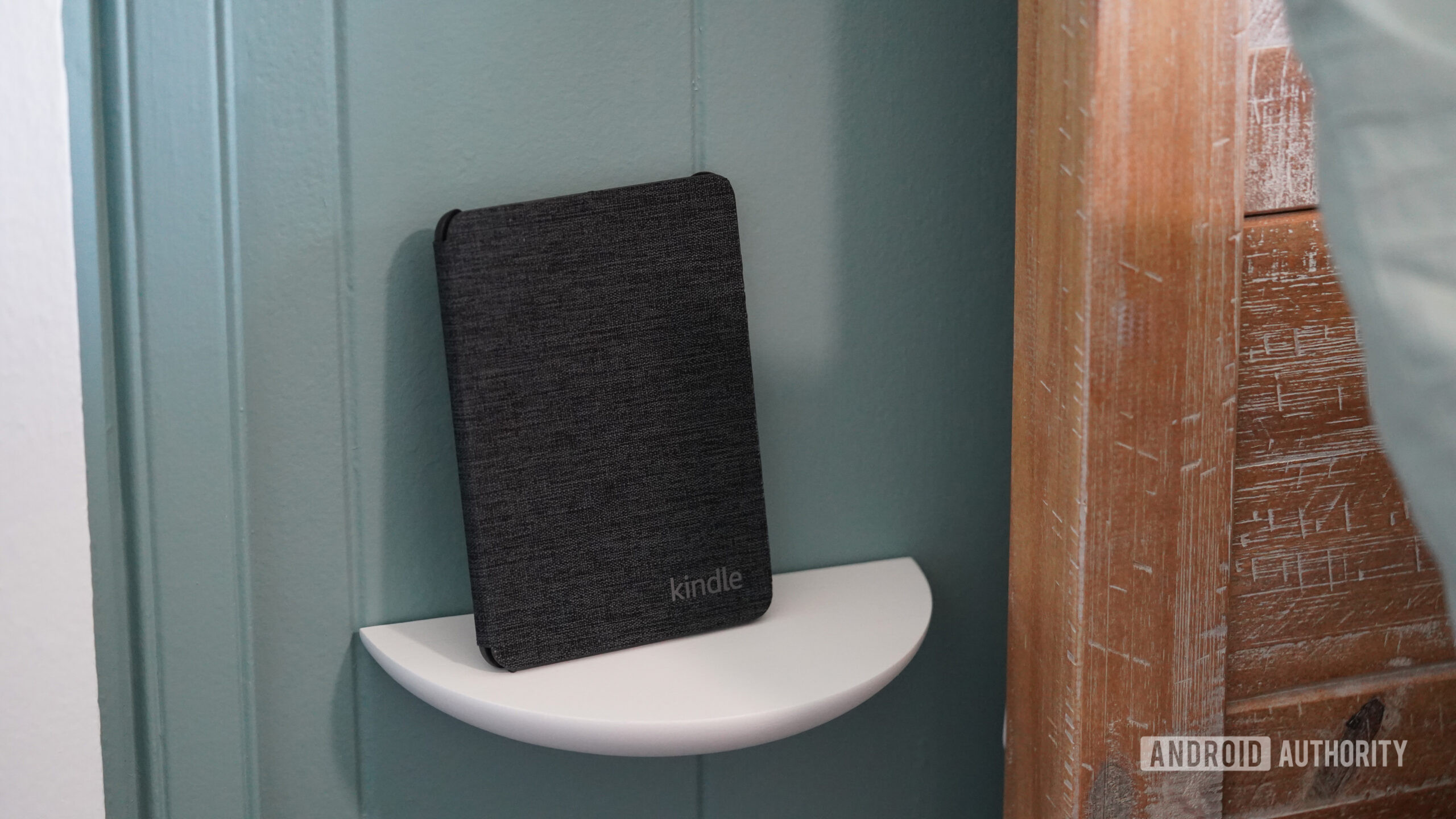 Um Kindle fica em uma pequena prateleira dedicada.