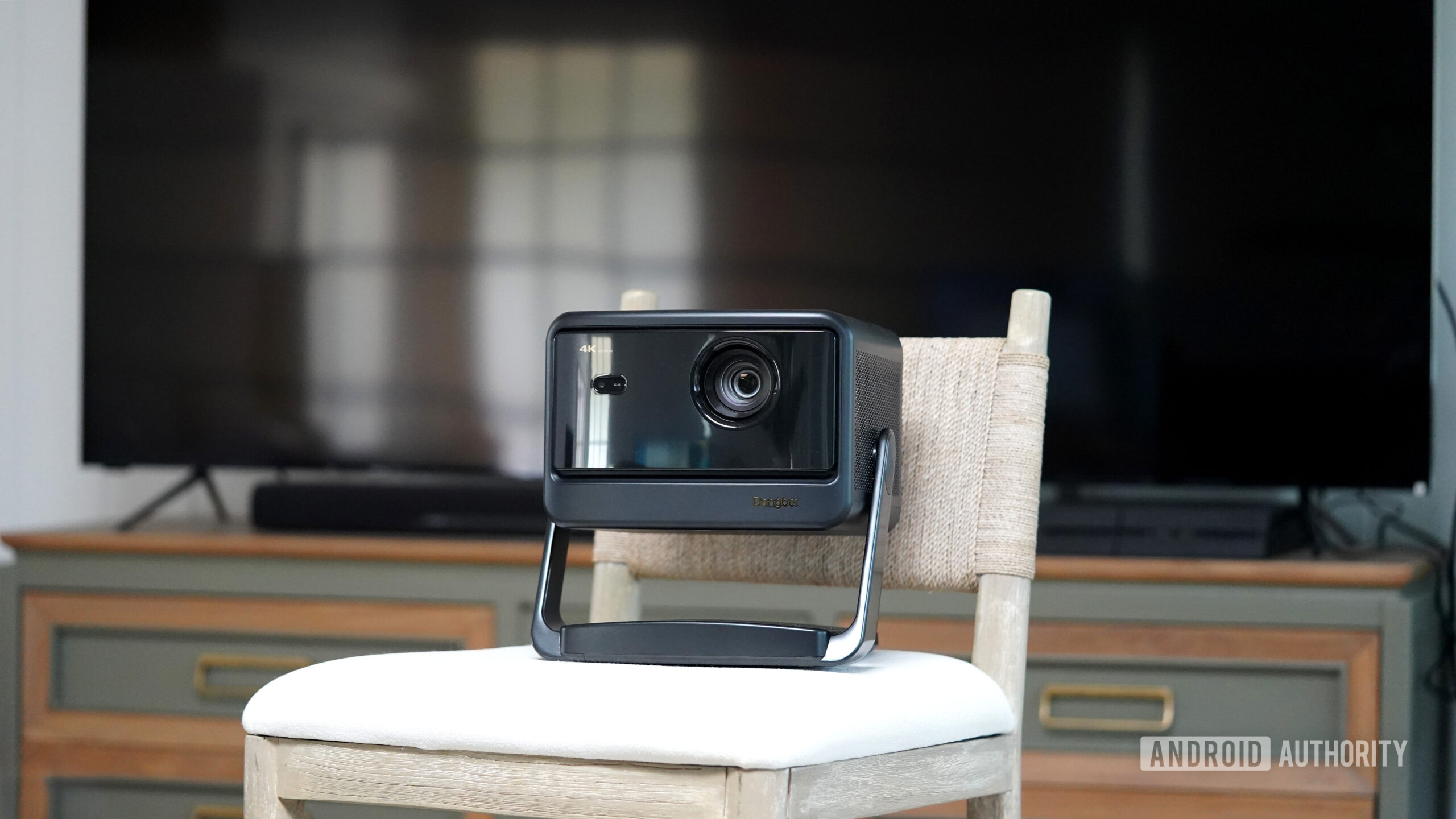 Um projetor portátil fica em frente a uma TV moderna.